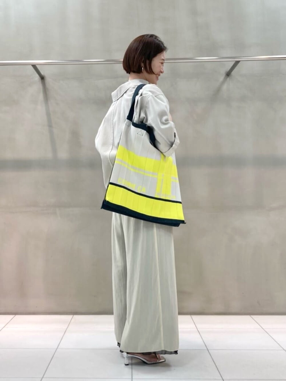 グレー系のシャツ/ブラウス、グレー系のその他パンツ、イエロー系のトートバッグを着用したレディースの春コーディネートの3枚目の写真