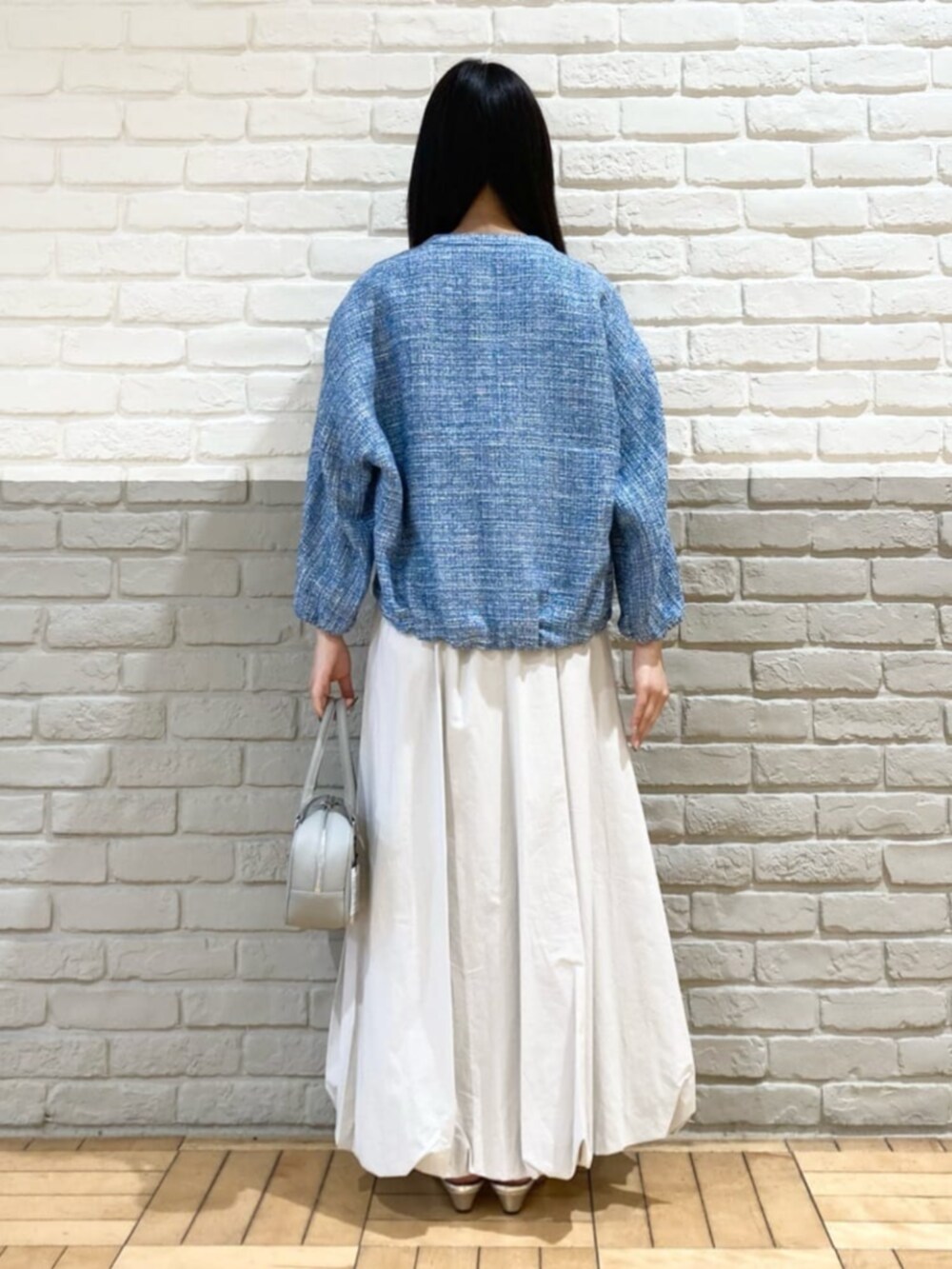 グレー系のスカート、ホワイト系のTシャツ/カットソー、グレー系のボストンバッグを着用したレディースの春コーディネートの4枚目の写真