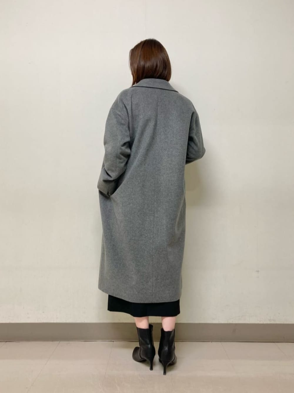 レッド系のニット/セーター、ブラック系のスカート、グレー系のチェスターコートを着用したレディースの冬コーディネートの3枚目の写真