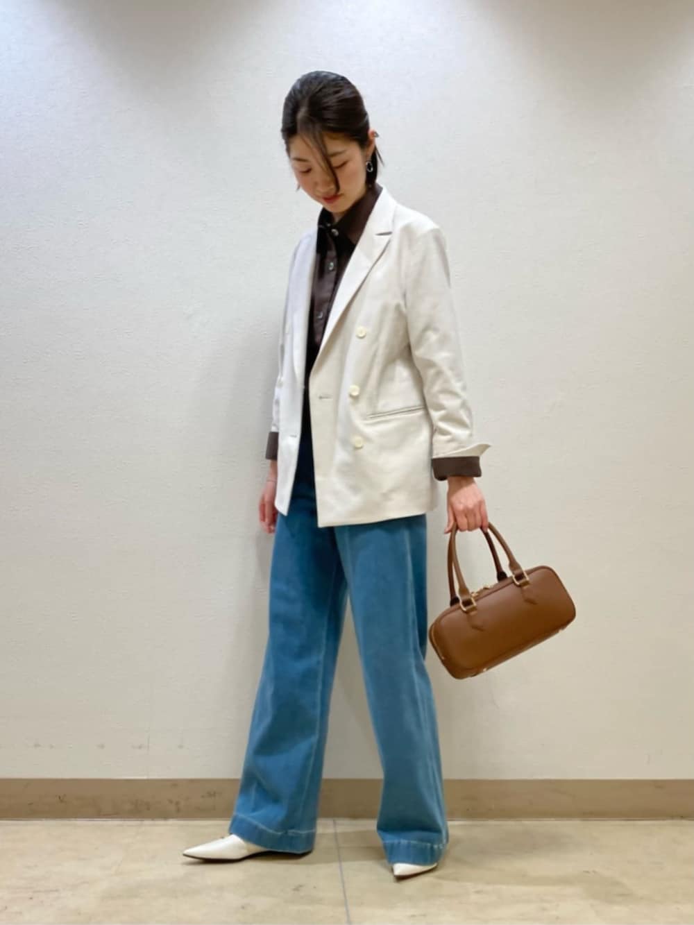 ブルー系のデニムパンツ、ホワイト系のテーラードジャケット、ブラック系のボストンバッグを着用したレディースの春コーディネートの3枚目の写真