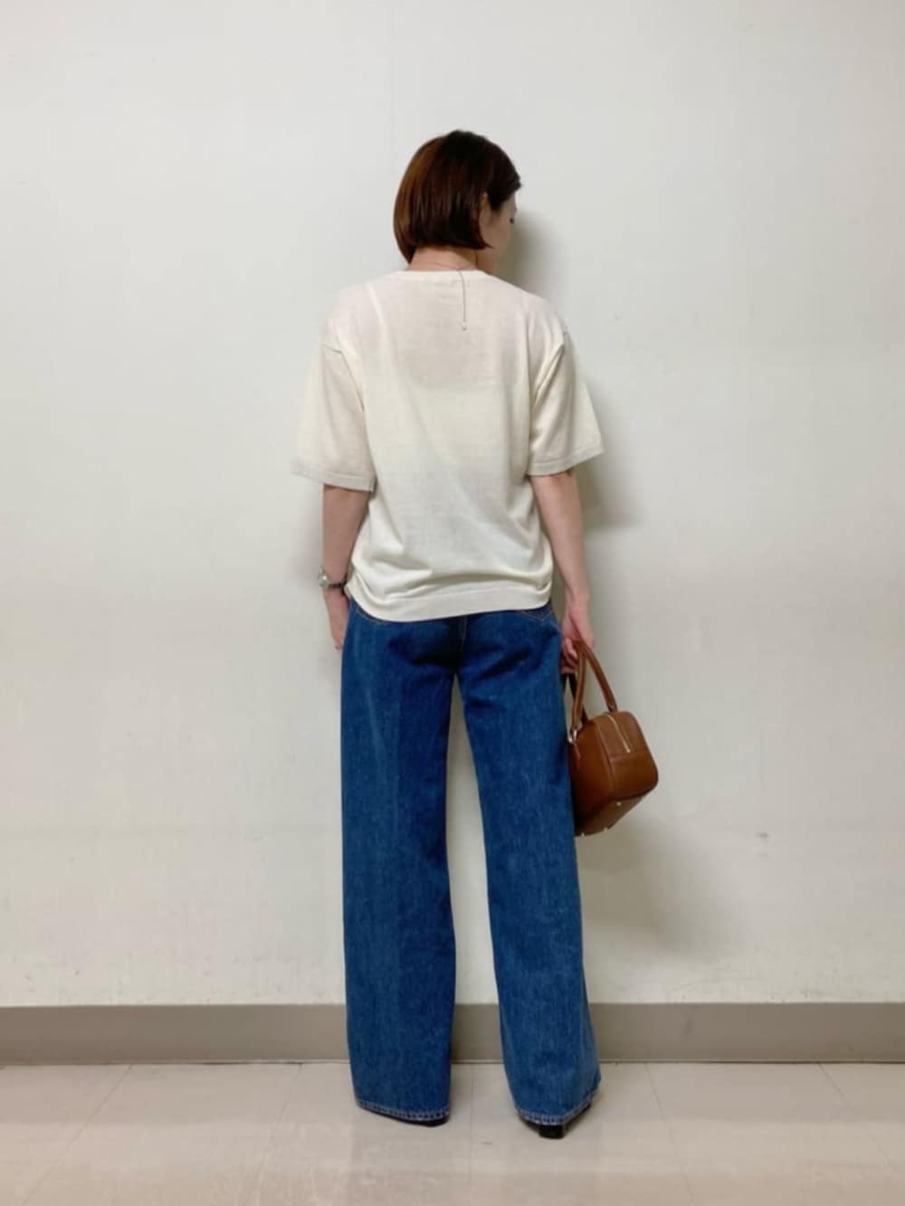 ブラウン系のボストンバッグ、ブルー系のデニムパンツ、ホワイト系のニット/セーターを着用したレディースの春コーディネートの7枚目の写真