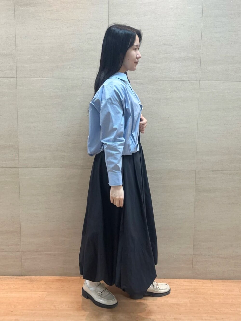 ブラック系のスカート、ブルー系のシャツ/ブラウス、シルバー系のタンクトップを着用したレディースの春コーディネートの3枚目の写真