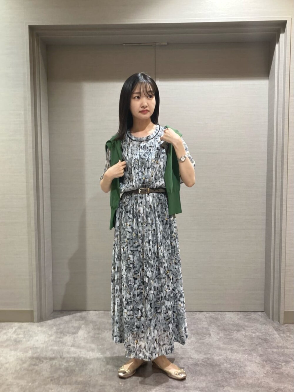 ブラック系のワンピース、グリーン系のニット/セーター、ブラック系のベルトを着用したレディースの夏コーディネートの2枚目の写真