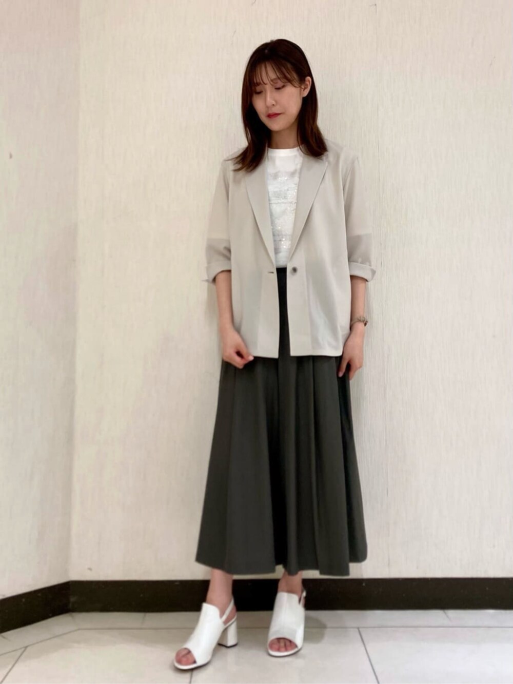 ベージュ系のテーラードジャケット、ホワイト系のTシャツ/カットソー、グリーン系のパンツを着用したレディースの夏コーディネートの2枚目の写真