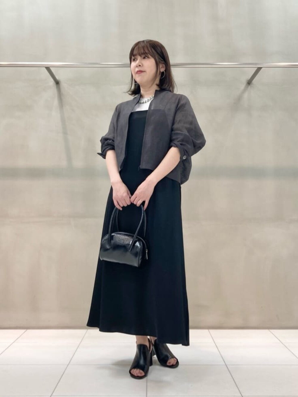 ブラック系のサンダル、ブラック系のワンピース、シルバー系のネックレスを着用したレディースの夏コーディネートの2枚目の写真