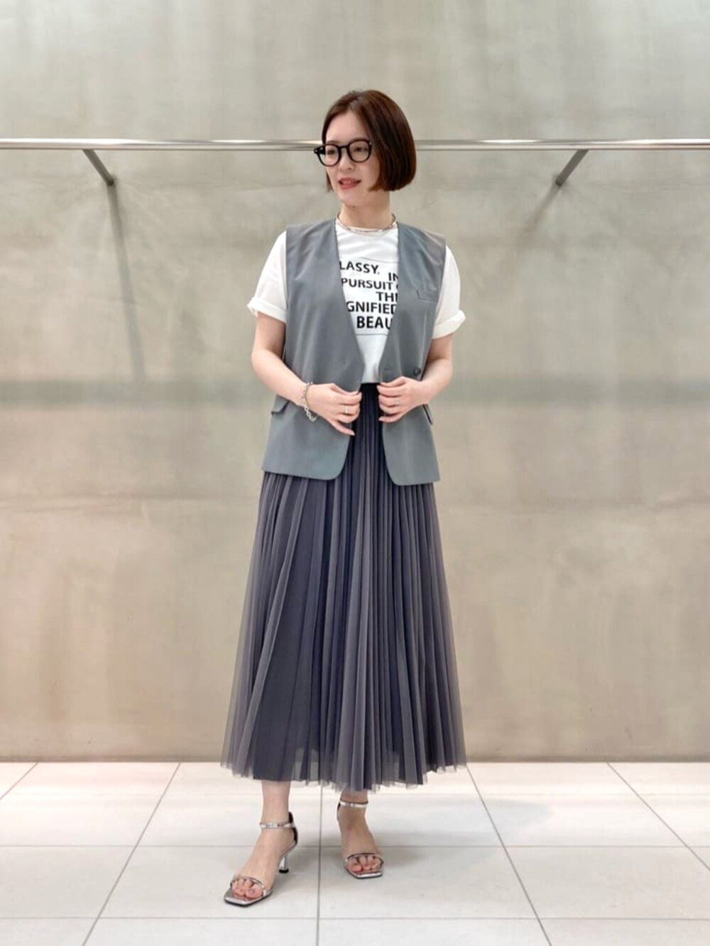 ブルー系のスカート、ホワイト系のTシャツ/カットソー、ブラック系のベストを着用したレディースの春コーディネートの2枚目の写真