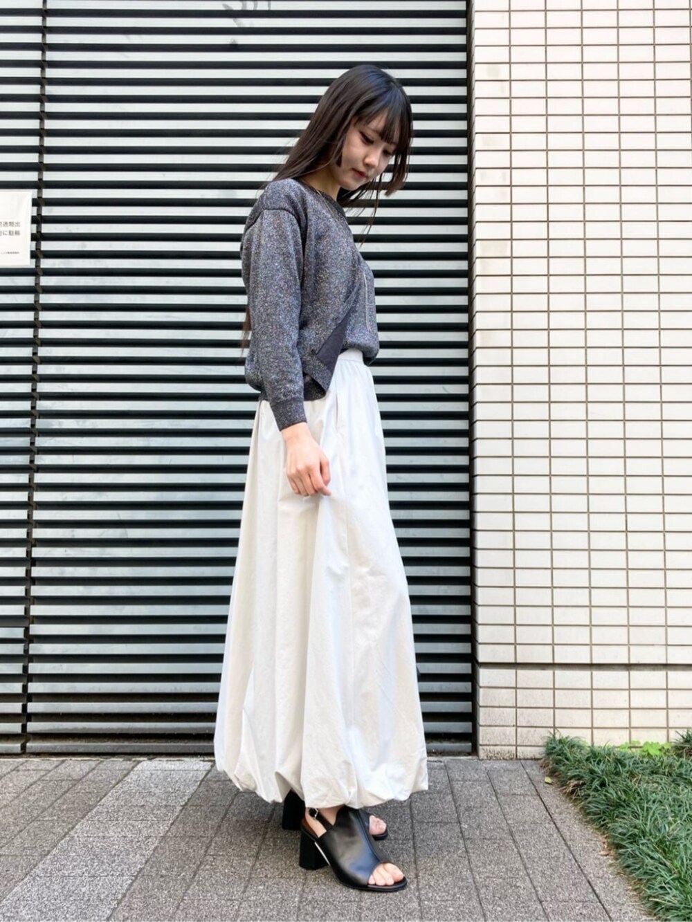 ホワイト系のショルダーバッグ、ベージュ系のスカート、ブラック系のサンダルを着用したレディースの夏コーディネートの3枚目の写真