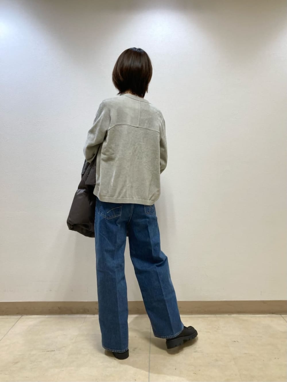 ブルー系のデニムパンツ、グレー系のダウンジャケット/コート、ベージュ系のカーディガン/ボレロを着用したレディースの冬コーディネートの8枚目の写真