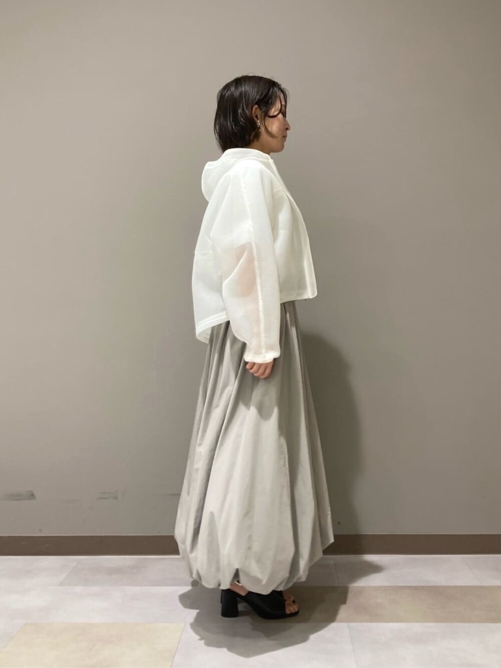 ベージュ系のスカート、ホワイト系のTシャツ/カットソー、ブラック系のサンダルを着用したレディースの春コーディネートの4枚目の写真