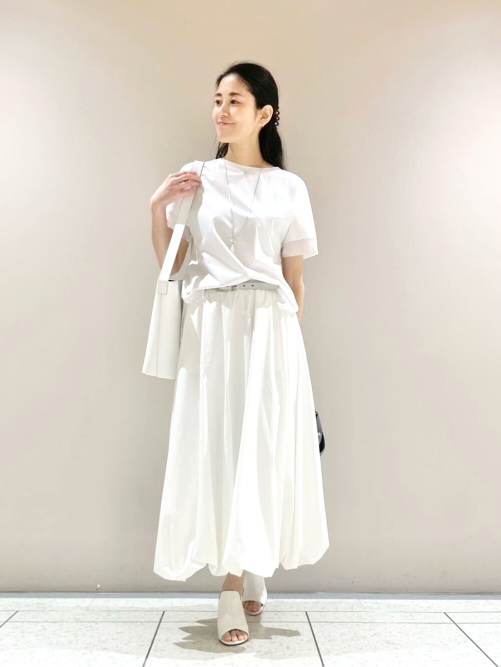 ホワイト系のスカート、ブラック系のベスト、ホワイト系のサンダルを着用したレディースの春コーディネートの4枚目の写真