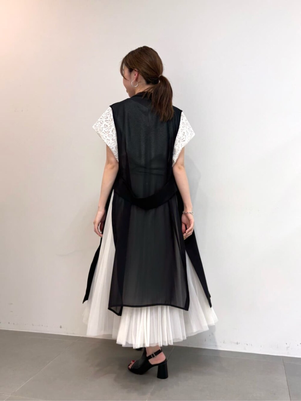 グレー系のスカート、ブラック系のサンダル、ブラック系のベストを着用したレディースの春コーディネートの5枚目の写真