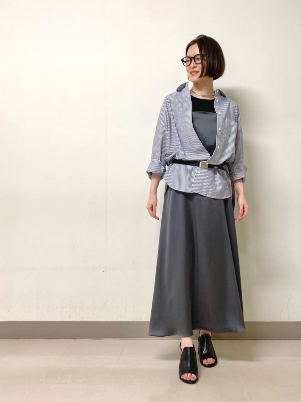 グレー系のワンピース、ブラック系のサンダル、ブルー系のシャツ/ブラウスを着用したレディースの春コーディネートの2枚目の写真