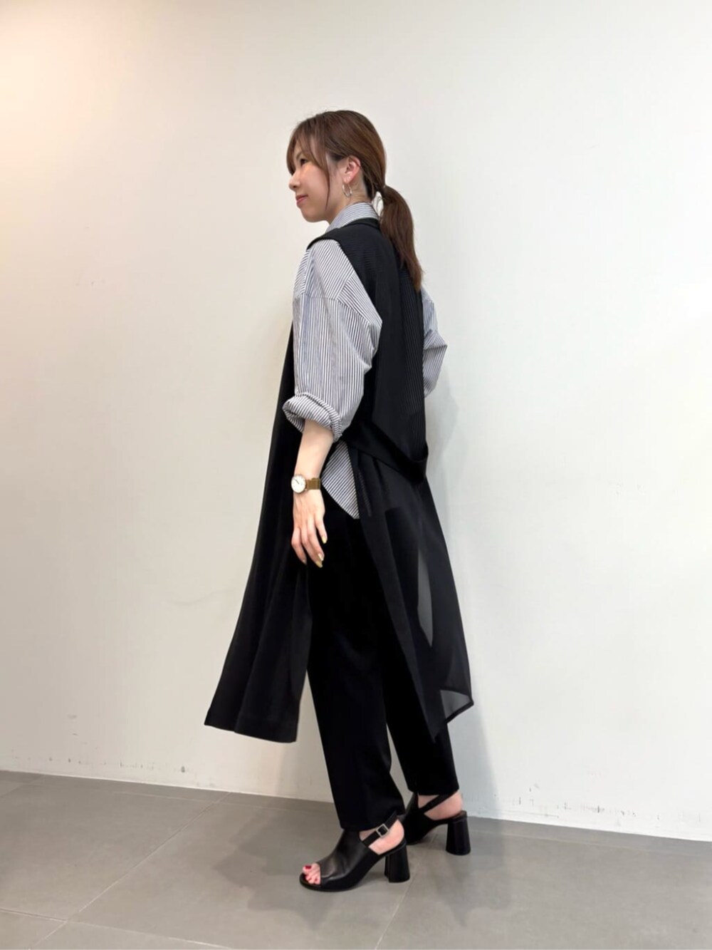 ブルー系のシャツ/ブラウス、ブラック系のサンダル、ブラック系のベストを着用したレディースの春コーディネートの6枚目の写真