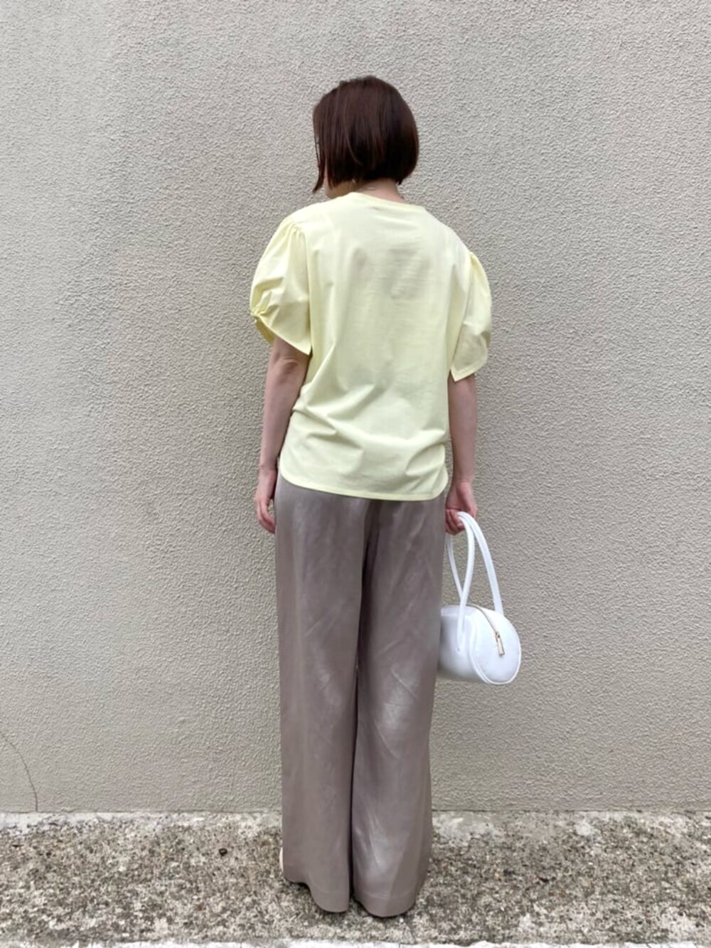 イエロー系のTシャツ/カットソー、ベージュ系のその他パンツ、ホワイト系のバッグを着用したレディースの夏コーディネートの6枚目の写真