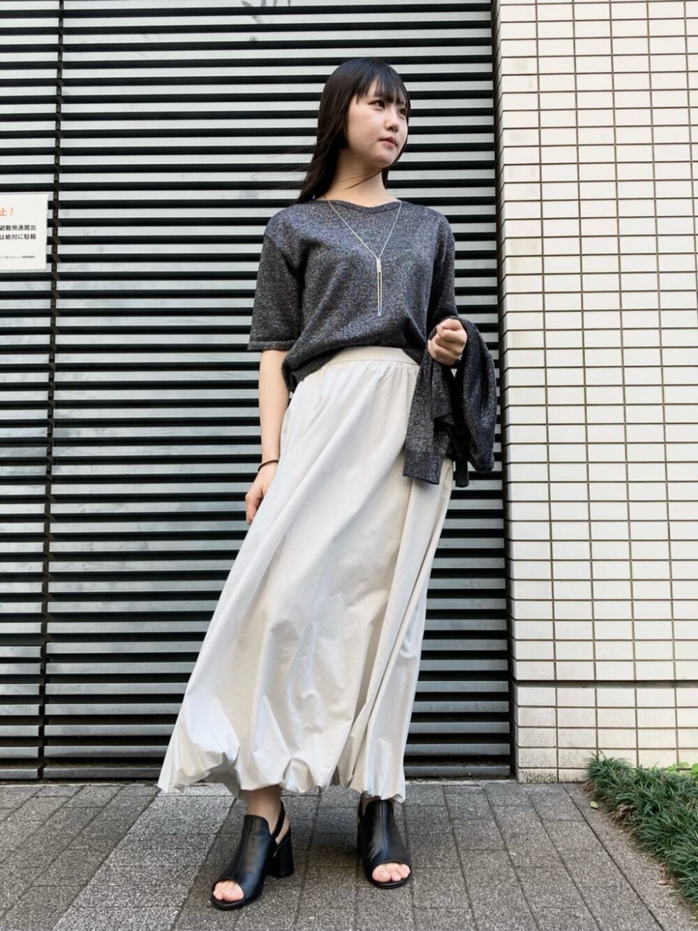 ホワイト系のショルダーバッグ、ベージュ系のスカート、ブラック系のサンダルを着用したレディースの夏コーディネートの2枚目の写真