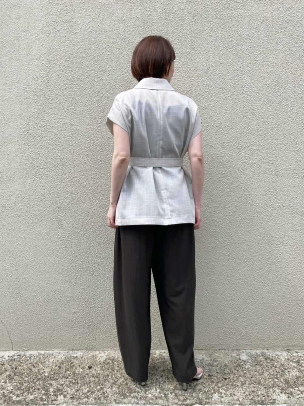 ブラウン系のキャミソール、ホワイト系のベスト、ブラウン系のパンツを着用したレディースの夏コーディネートの5枚目の写真