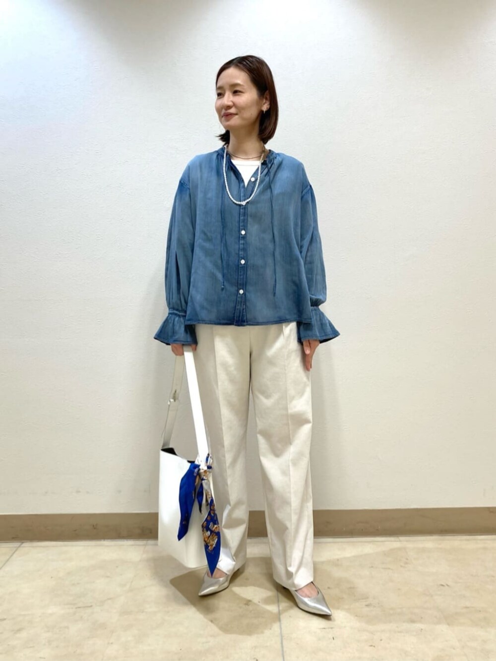 ホワイト系のショルダーバッグ、シルバー系のパンプス、ホワイト系のスラックスを着用したレディースの春コーディネートの3枚目の写真
