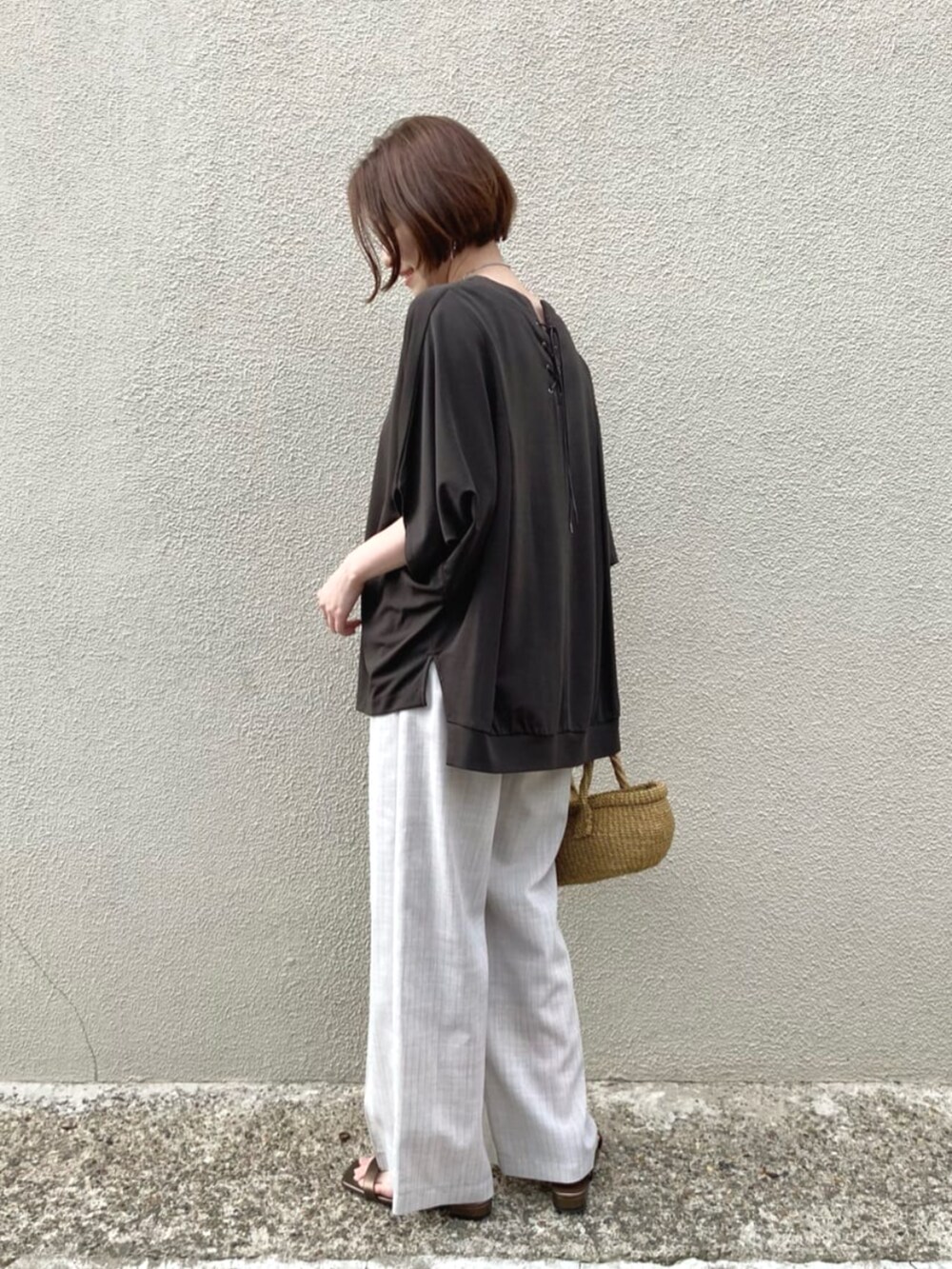 ホワイト系のスラックス、シルバー系のネックレスを着用したレディースの夏コーディネートの3枚目の写真