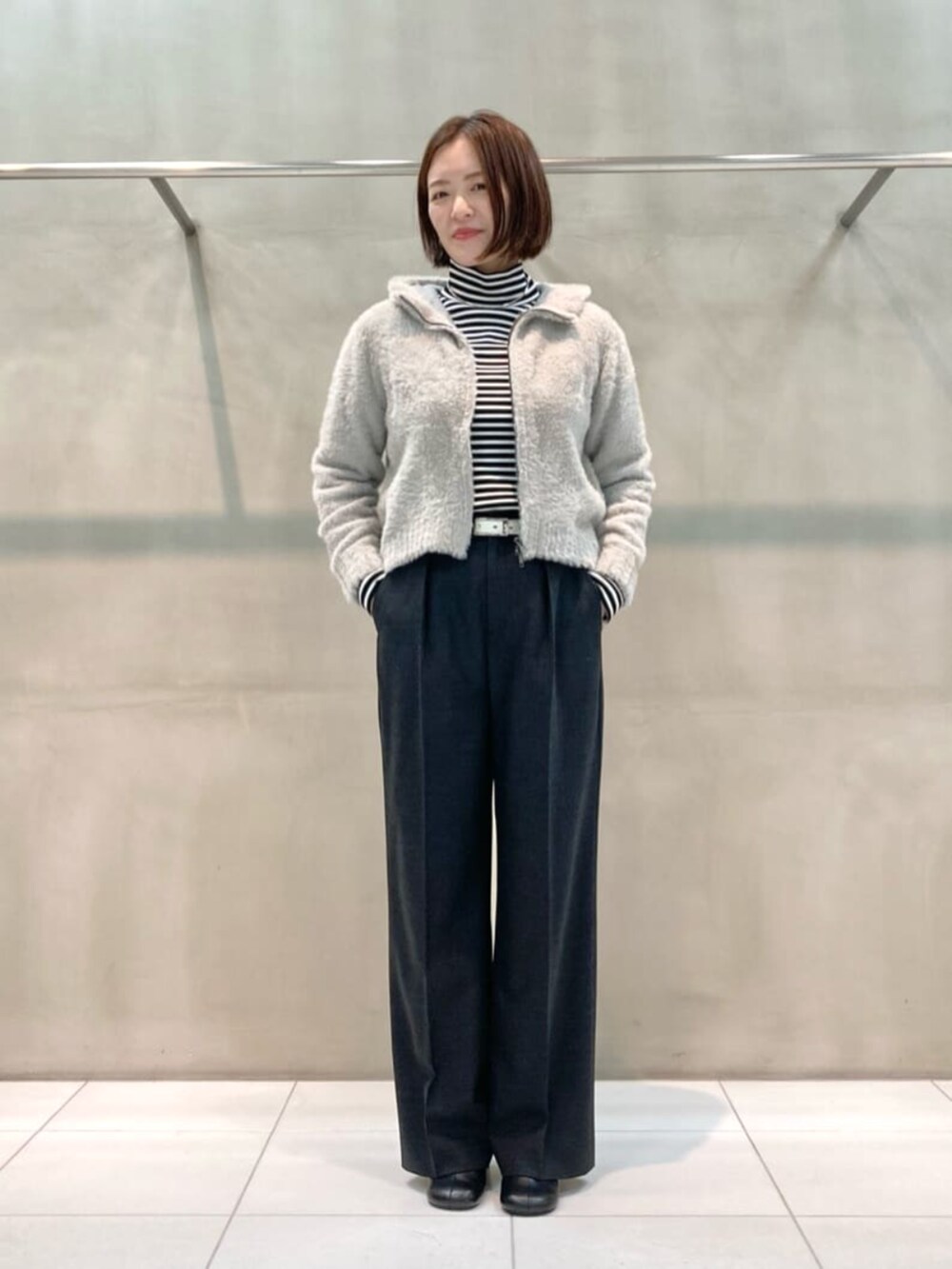 グレー系のスーツパンツ、ブラック系のブーツ、ベージュ系のパーカーを着用したレディースの秋コーディネートの4枚目の写真