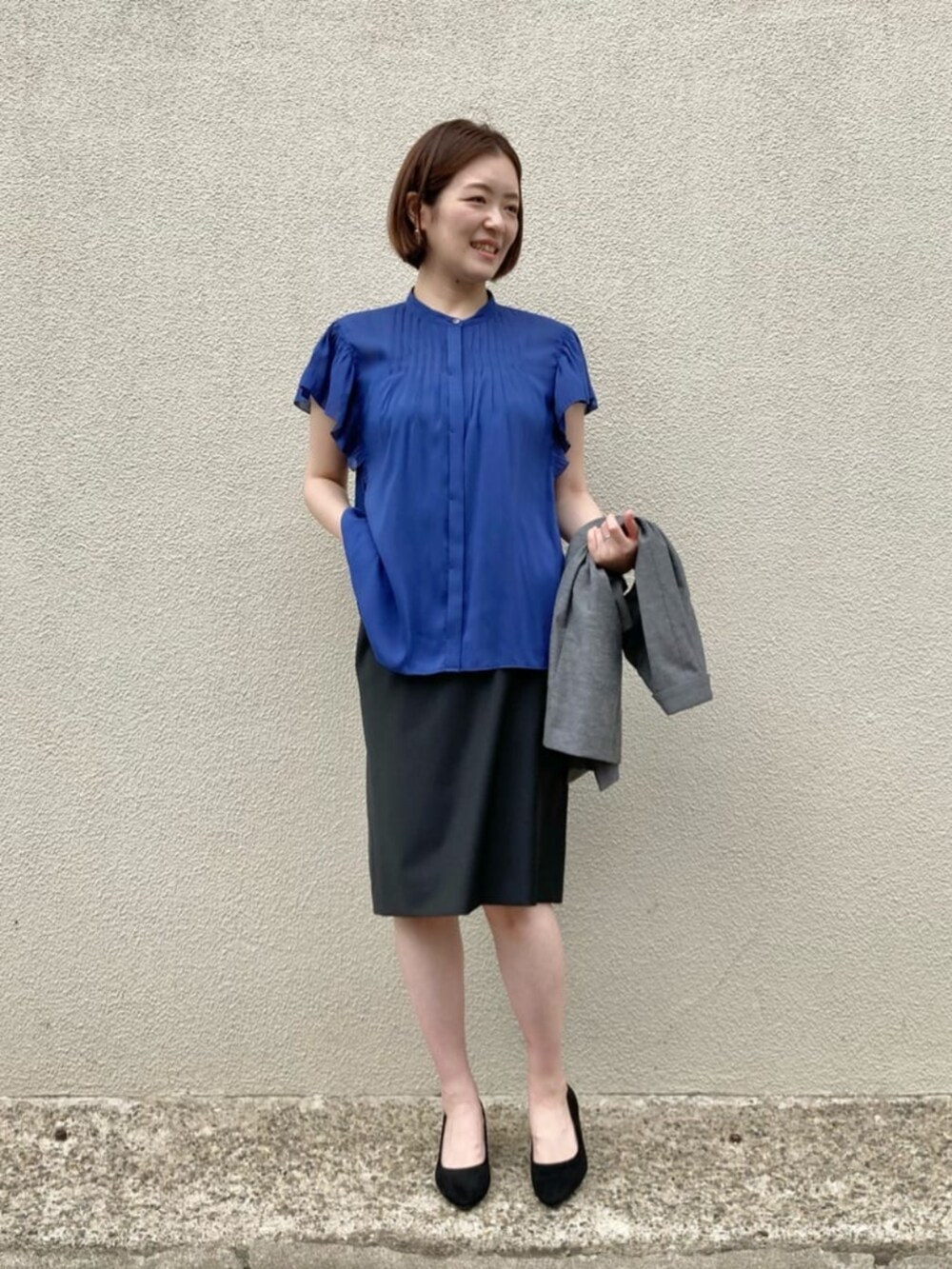 ブルー系のシャツ/ブラウス、グレー系のテーラードジャケット、ブラック系のスーツスカートを着用したレディースの秋コーディネートの7枚目の写真