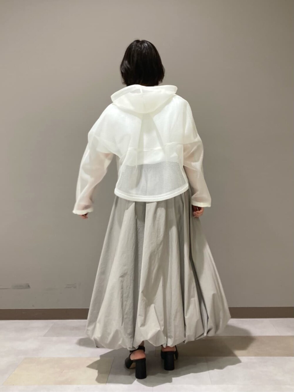 ベージュ系のスカート、ホワイト系のTシャツ/カットソー、ブラック系のサンダルを着用したレディースの春コーディネートの6枚目の写真