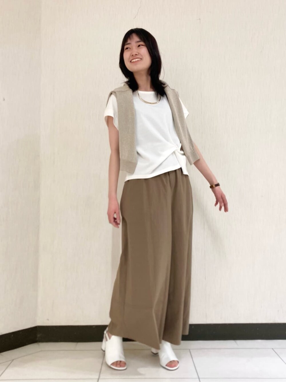 ベージュ系のカーディガン/ボレロ、ホワイト系のサンダル、ホワイト系のTシャツ/カットソーを着用したレディースの春コーディネートの4枚目の写真