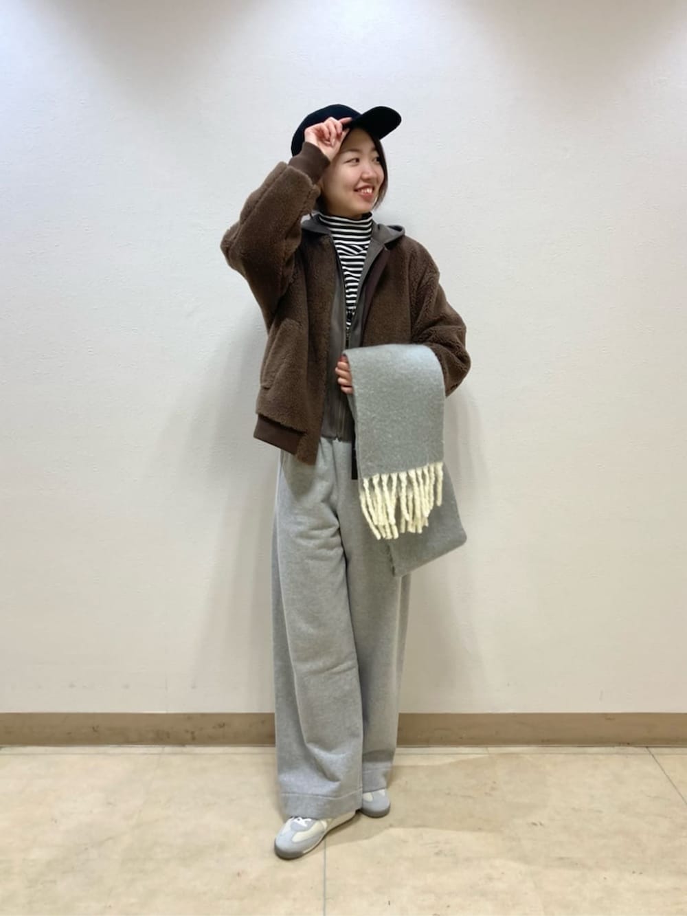 ブラウン系のブルゾン、グレー系のその他パンツ、ブラック系のキャップを着用したレディースの冬コーディネートの2枚目の写真