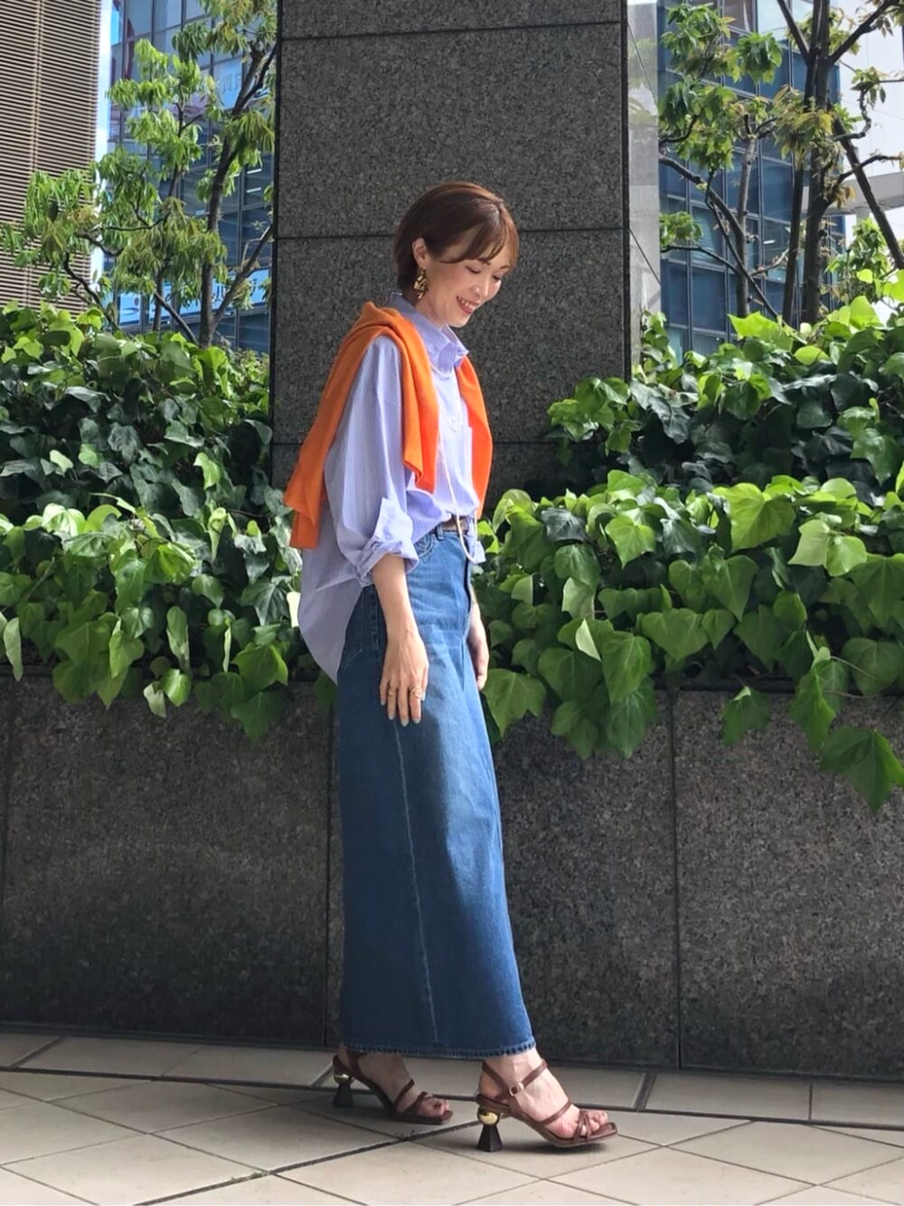 オレンジ系のニット/セーター、ブルー系のシャツ/ブラウス、ブルー系のスカートを着用したレディースの春コーディネートの4枚目の写真