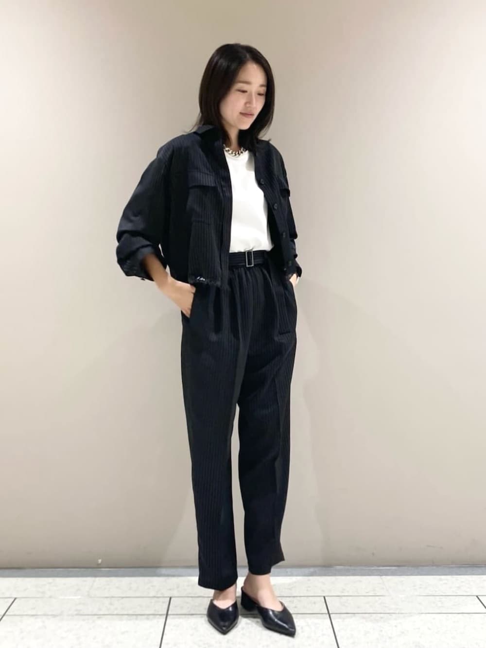 ブラック系のブルゾン、ブラック系のスラックス、ホワイト系のTシャツ/カットソーを着用したレディースの春コーディネートの2枚目の写真