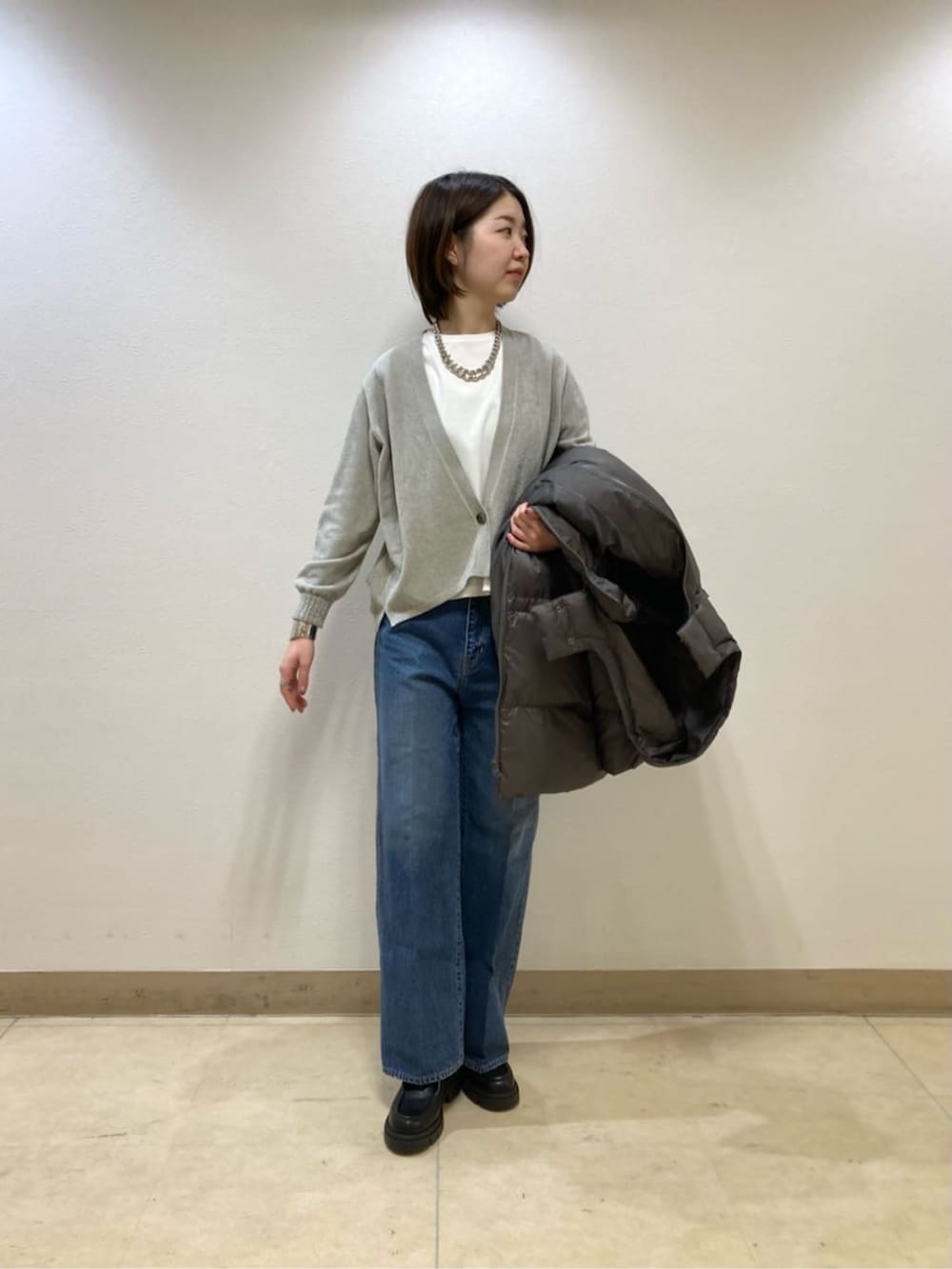 ブルー系のデニムパンツ、グレー系のダウンジャケット/コート、ベージュ系のカーディガン/ボレロを着用したレディースの冬コーディネートの7枚目の写真