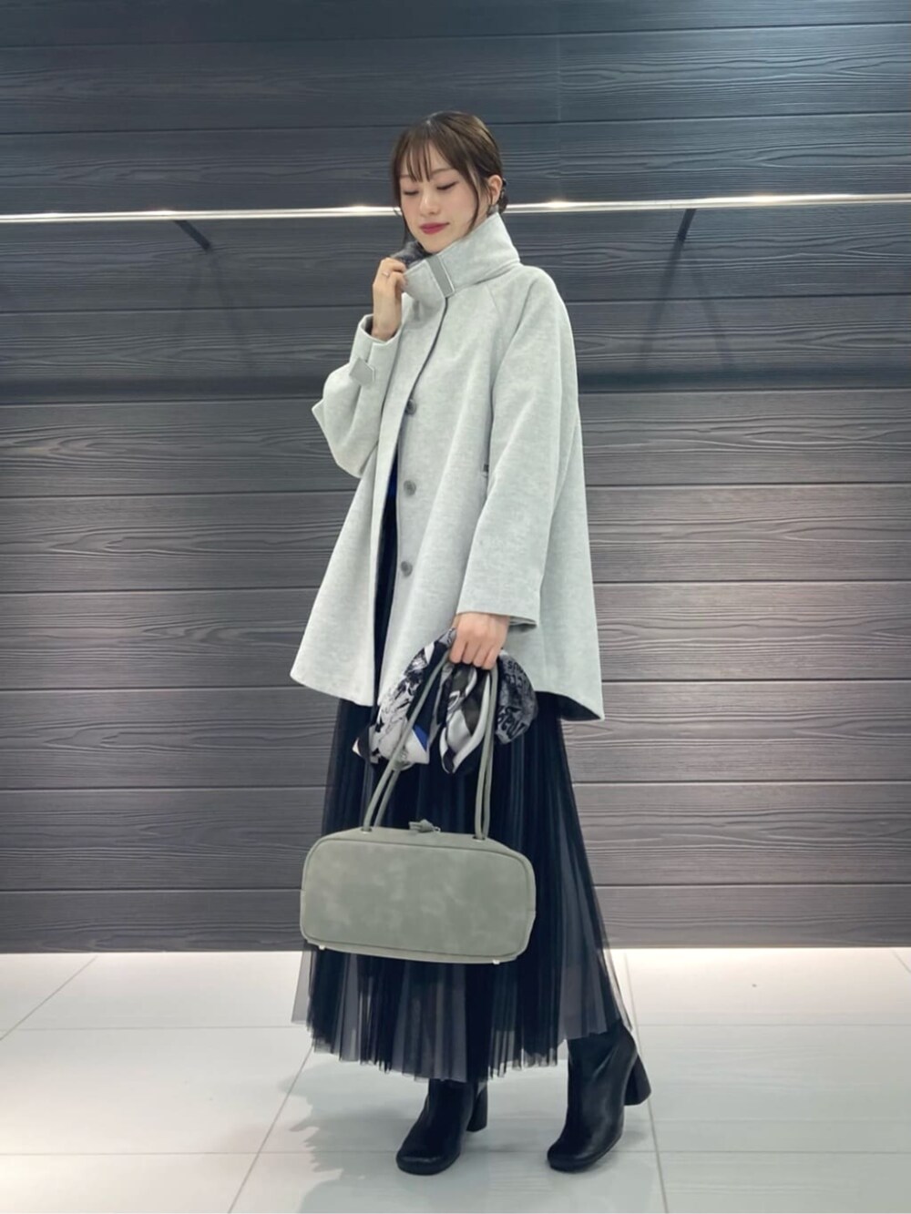 グレー系のスカート、グレー系のその他アウター、ブルー系のニット/セーターを着用したレディースの秋コーディネートの2枚目の写真