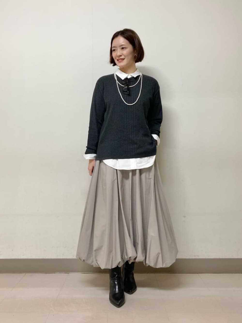 ベージュ系のスカート、グレー系のニット/セーター、ホワイト系のシャツ/ブラウスを着用したレディースの冬コーディネートの3枚目の写真