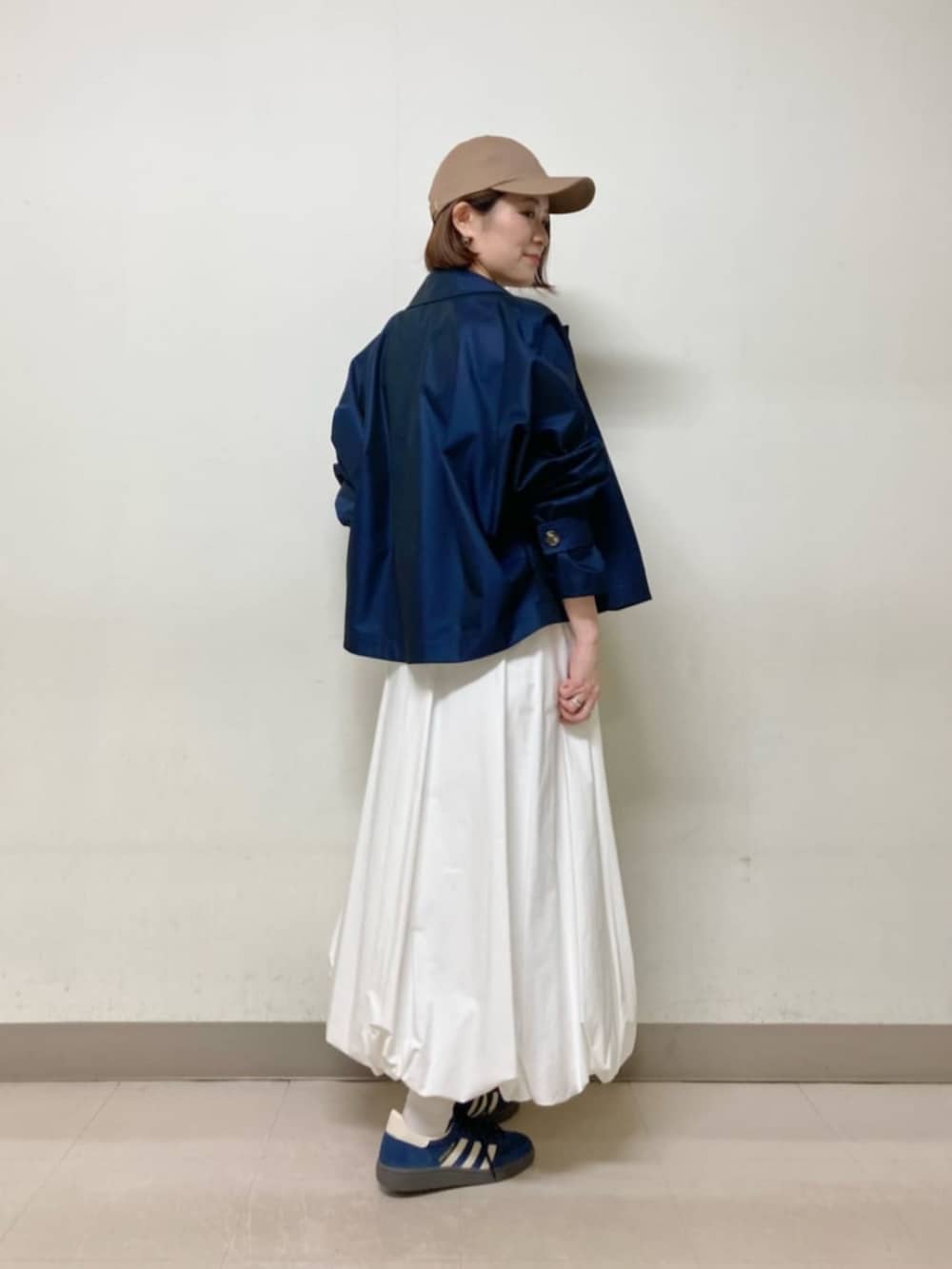 ホワイト系のスカート、ブルー系のブルゾン、イエロー系のキャップを着用したレディースの春コーディネートの4枚目の写真