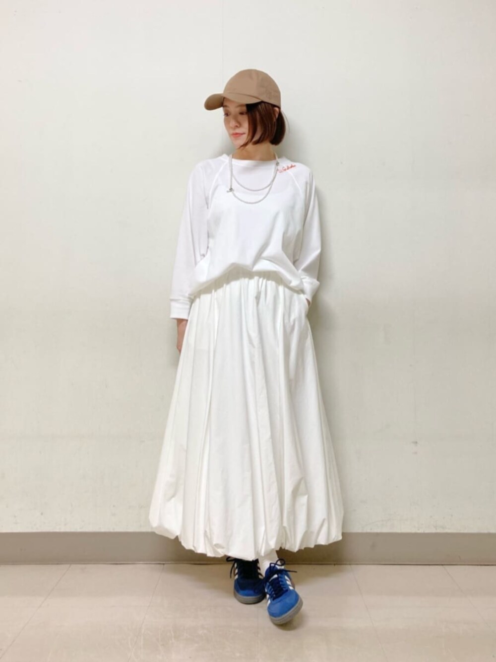 ホワイト系のスカート、ブルー系のブルゾン、イエロー系のキャップを着用したレディースの春コーディネートの6枚目の写真