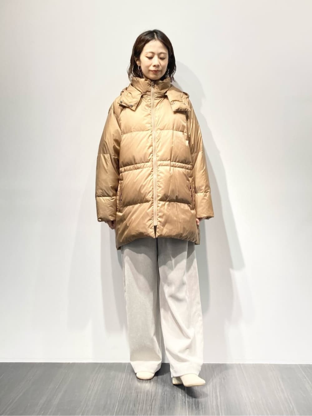 イエロー系のダウンジャケット/コート、ベージュ系のその他パンツ、ホワイト系のブーツを着用したレディースの秋コーディネートの2枚目の写真