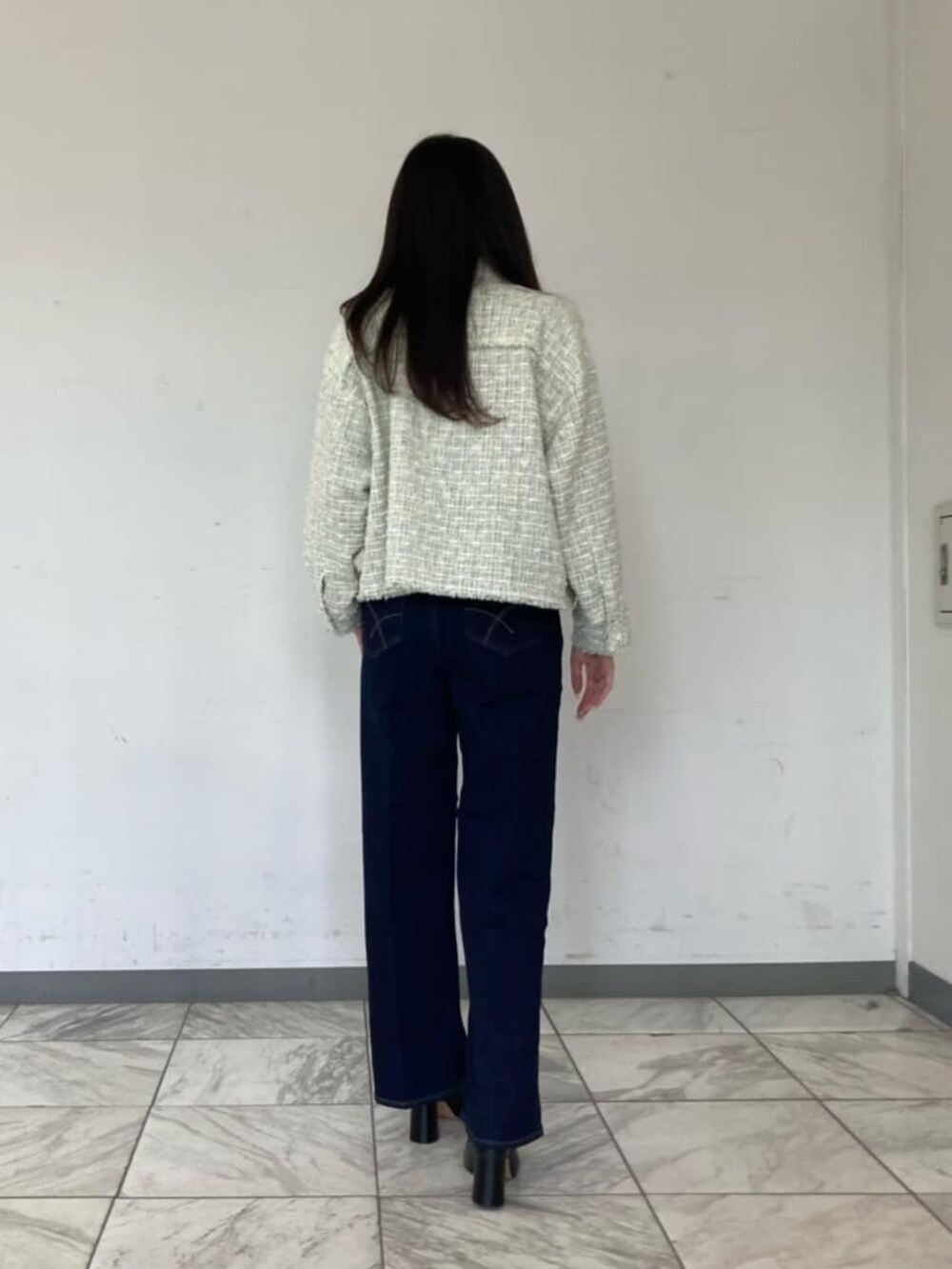ブルー系のデニムパンツ、グリーン系のニット/セーター、ブラック系のサンダルを着用したレディースの春コーディネートの4枚目の写真