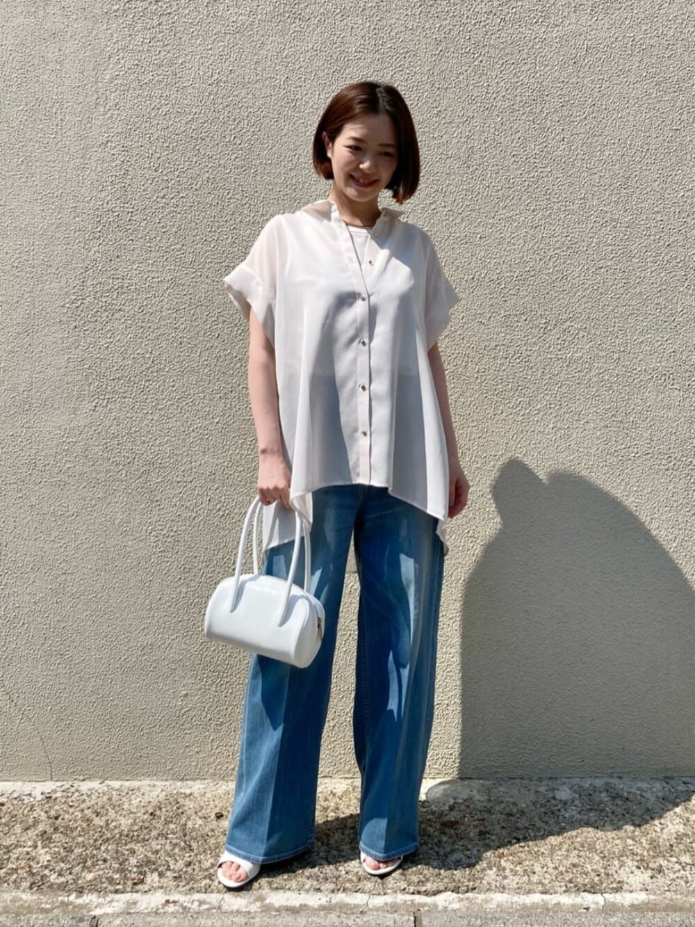 ブルー系のデニムパンツ、ホワイト系のサンダル、ホワイト系のシャツ/ブラウスを着用したレディースの夏コーディネートの2枚目の写真