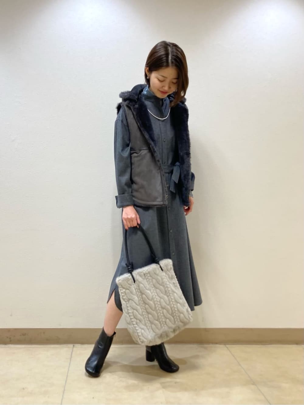 グレー系のベスト、グレー系のワンピースを着用したレディースの秋コーディネートの2枚目の写真