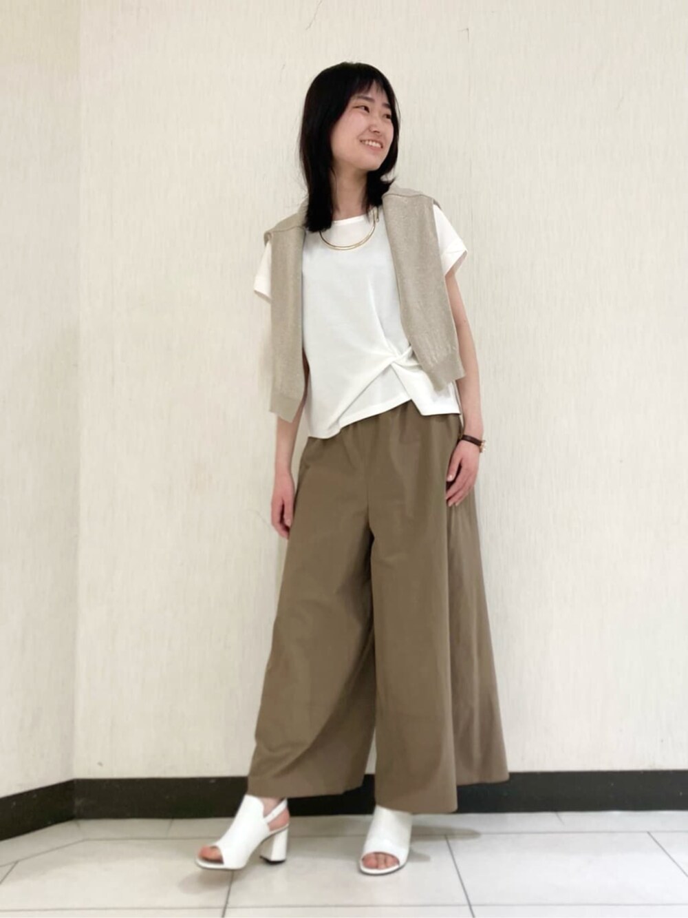 ベージュ系のカーディガン/ボレロ、ホワイト系のサンダル、ホワイト系のTシャツ/カットソーを着用したレディースの春コーディネートの2枚目の写真