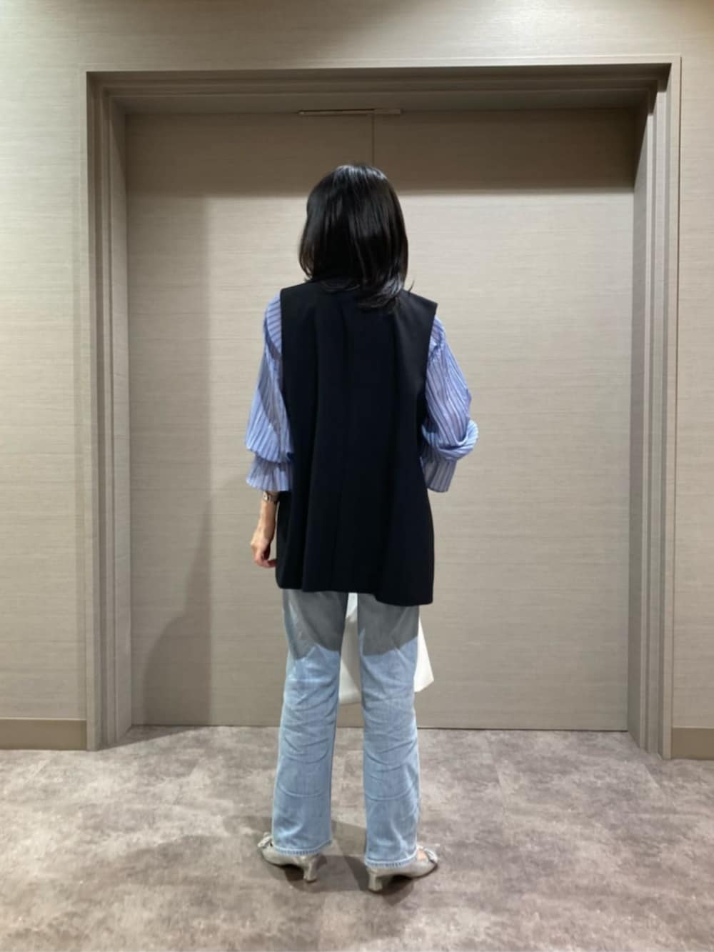 ホワイト系のショルダーバッグ、ブルー系のシャツ/ブラウス、ブラック系のベストを着用したレディースの春コーディネートの6枚目の写真