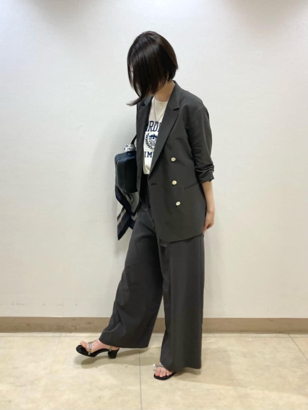 グレー系のテーラードジャケット、グレー系のその他パンツ、ホワイト系のニット/セーターを着用したレディースの春コーディネートの2枚目の写真