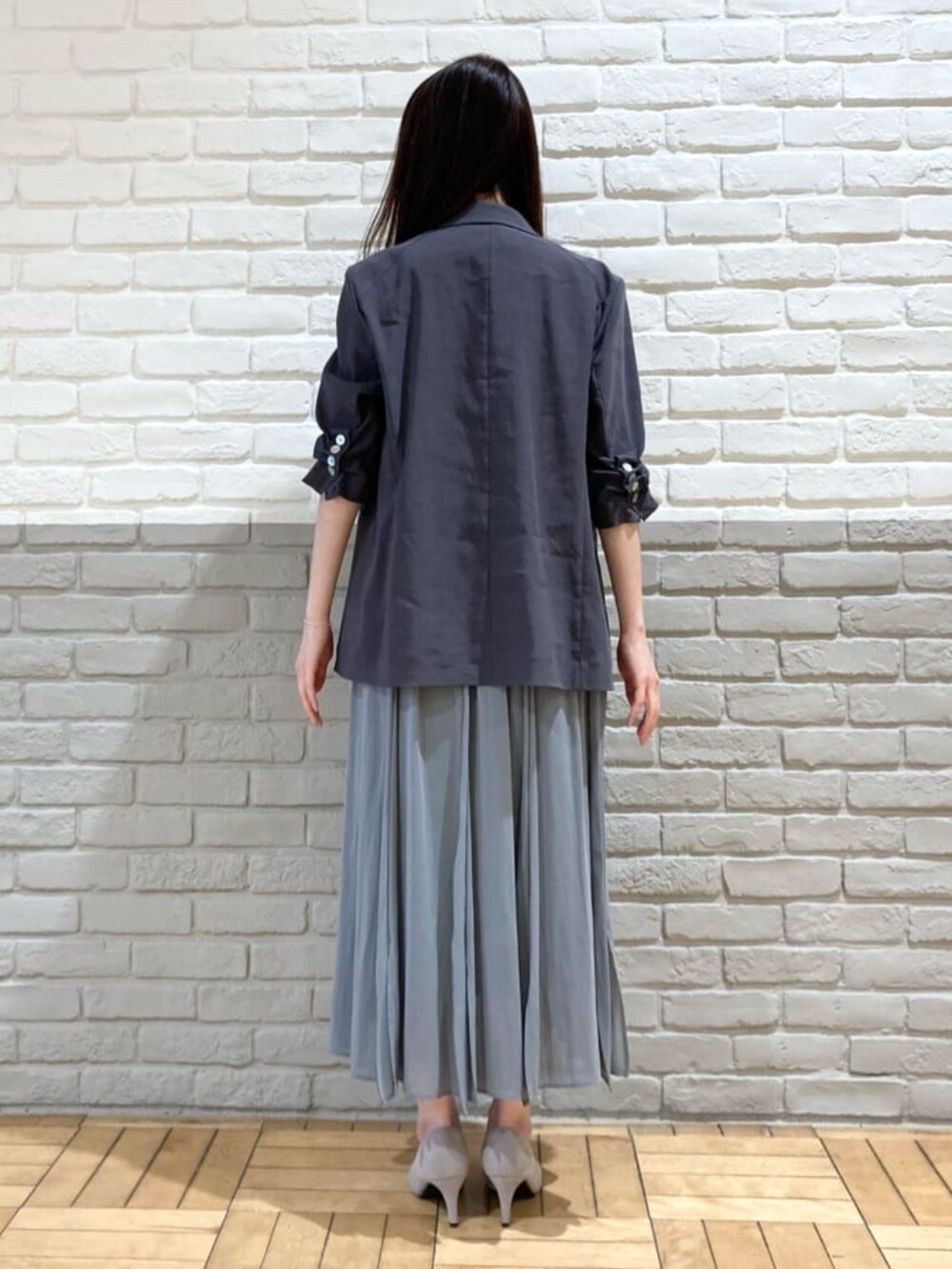 グレー系のテーラードジャケット、グリーン系のスカート、ブラック系のタンクトップを着用したレディースの春コーディネートの5枚目の写真