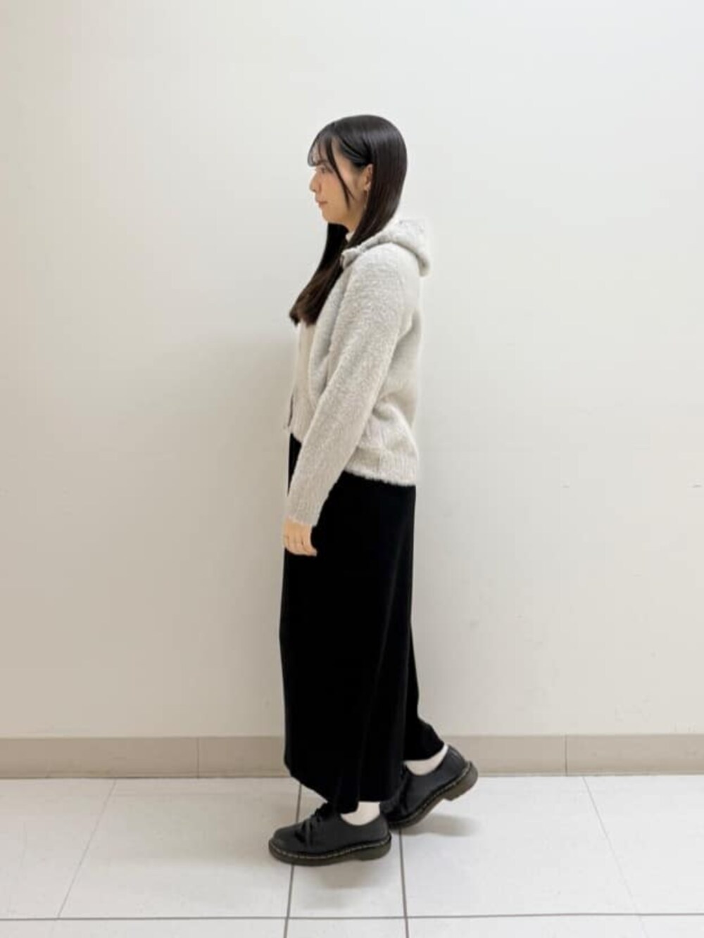 ベージュ系のパーカー、ブラック系のスカート、ブラック系のブルゾンを着用したレディースの冬コーディネートの5枚目の写真