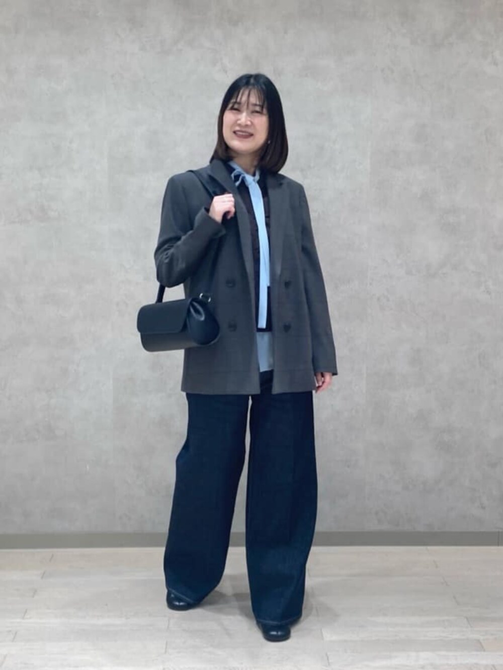 ブルー系のデニムパンツ、ブラック系のブーツ、グレー系のテーラードジャケットを着用したレディースの秋コーディネートの2枚目の写真