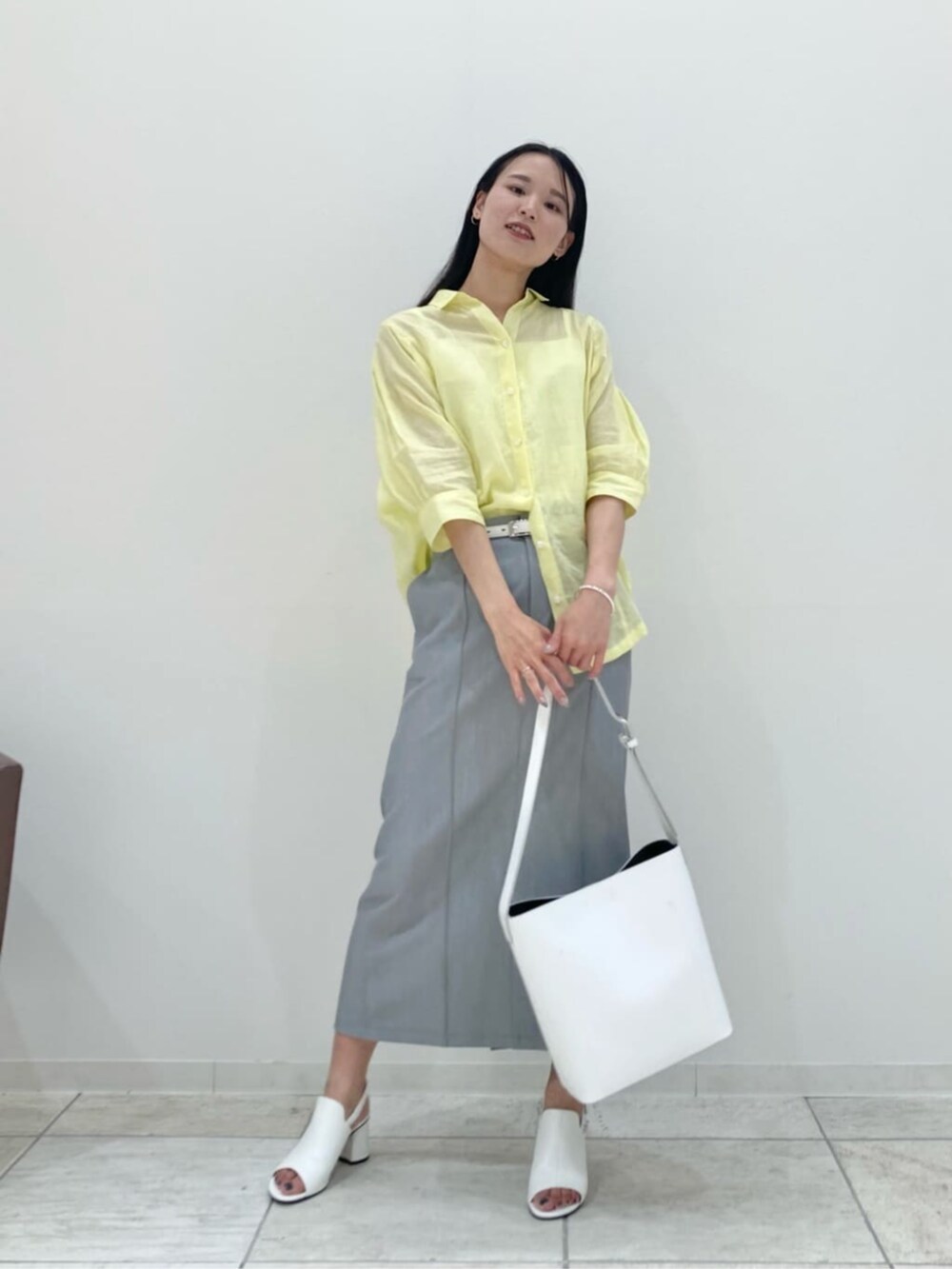 ホワイト系のショルダーバッグ、グレー系のスカート、ホワイト系のサンダルを着用したレディースの夏コーディネートの2枚目の写真