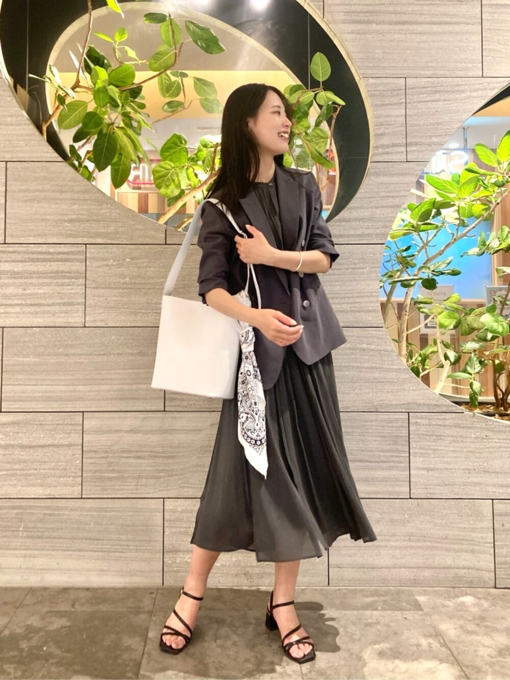 ホワイト系のショルダーバッグ、グレー系のテーラードジャケット、グリーン系のスカートを着用したレディースの春コーディネートの3枚目の写真