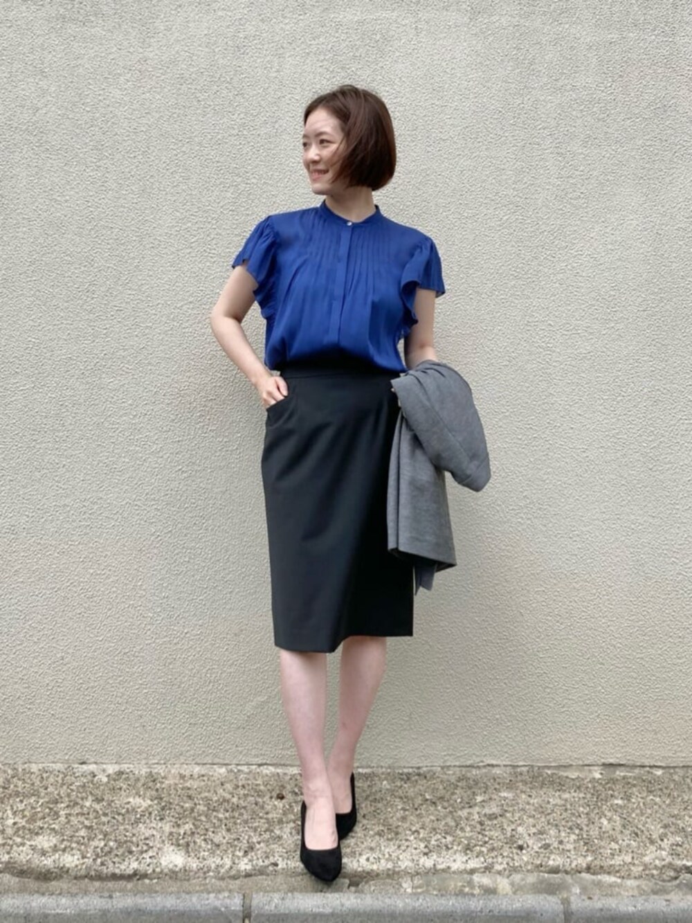 ブルー系のシャツ/ブラウス、グレー系のテーラードジャケット、ブラック系のスーツスカートを着用したレディースの秋コーディネートの4枚目の写真