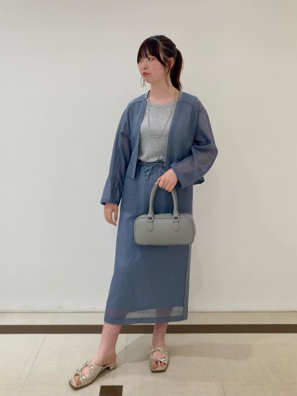 グレー系のボストンバッグ、ブルー系のブルゾン、ブルー系のスカートを着用したレディースの夏コーディネートの2枚目の写真