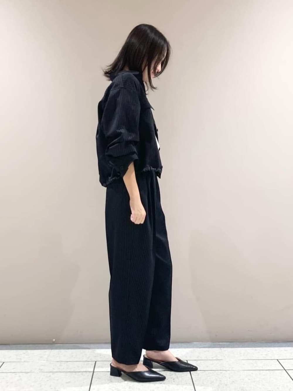 ブラック系のブルゾン、ブラック系のスラックス、ホワイト系のTシャツ/カットソーを着用したレディースの春コーディネートの3枚目の写真