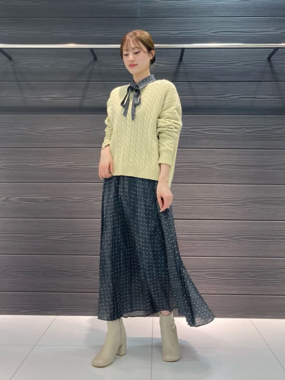 ホワイト系のブーツ、イエロー系のニット/セーター、グレー系のスカートを着用したレディースの冬コーディネートの2枚目の写真